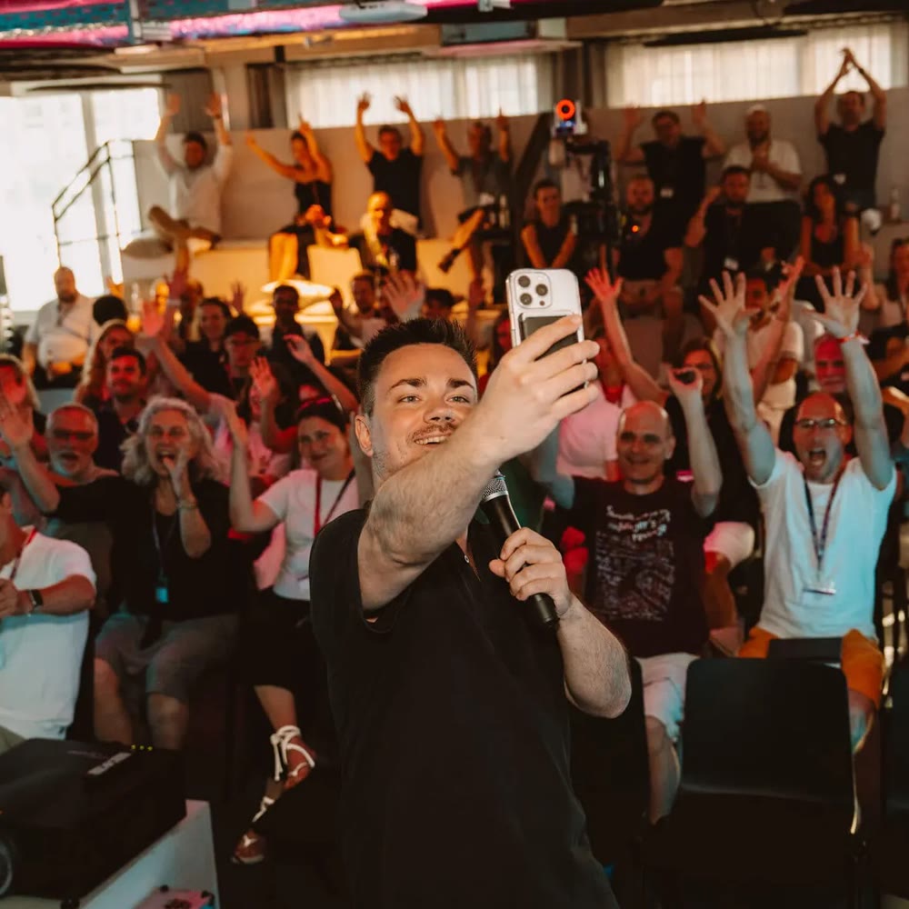 Andreas Pabst macht auf der Bühne der AI Nights ein Selfie mit dem Publikum
